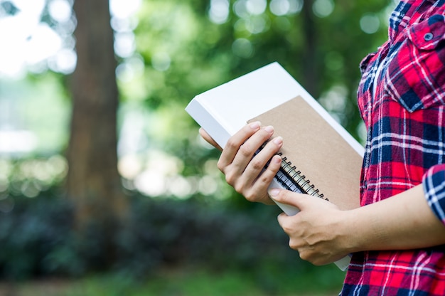 Foto giovane ragazza abbraccia il suo libro nella giungla verde