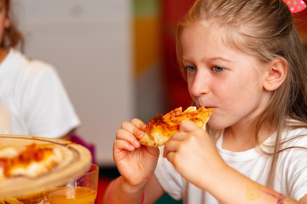 写真 屋内でのバースデーパーティーでピザを楽しんでいる若い女の子