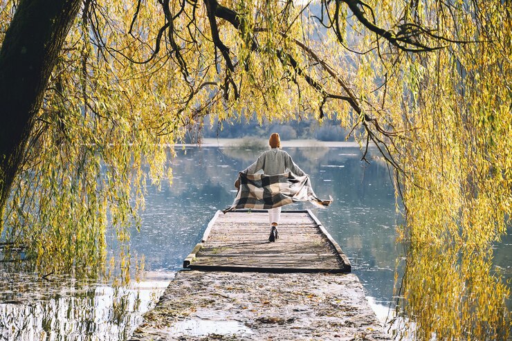 Young girl enjoying of beauty autumn in nature Woman wearing checkered scarf walking in fall season