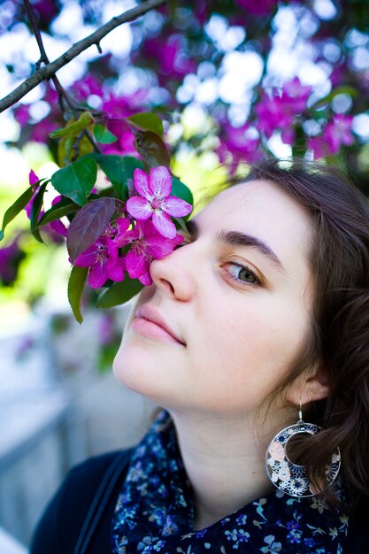 Young girl enjoying of blossoming tree flowers smell.