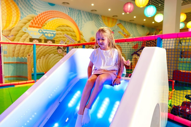 Young girl enjoying a colorful slide at an indoor playground