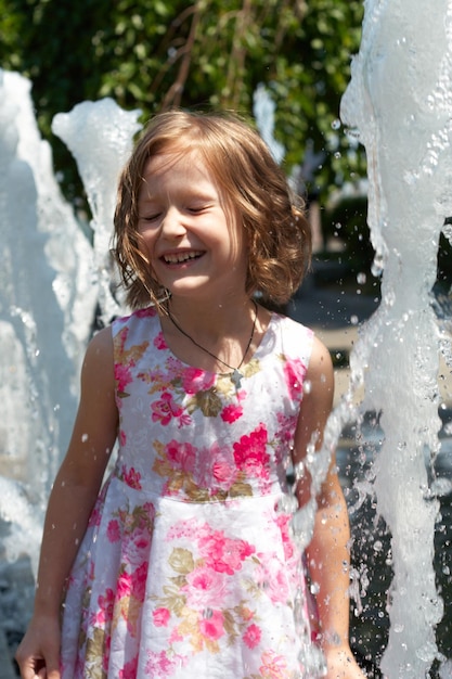 Young girl enjoys a summer playing at the park fountain