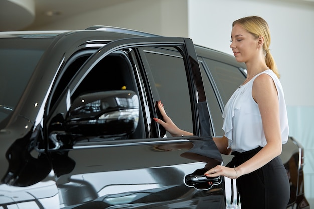 A young girl examines a car before buying it at a car dealership