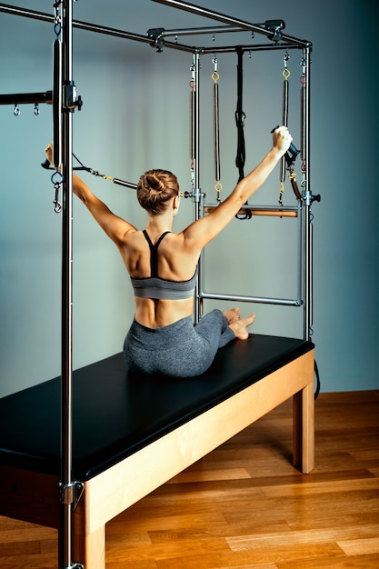 Young girl exercises on a bed of Pilates reformers