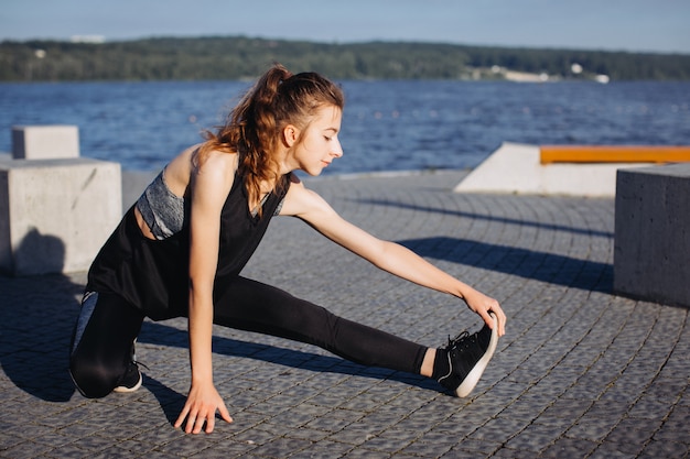 A young girl exercising by the lake 