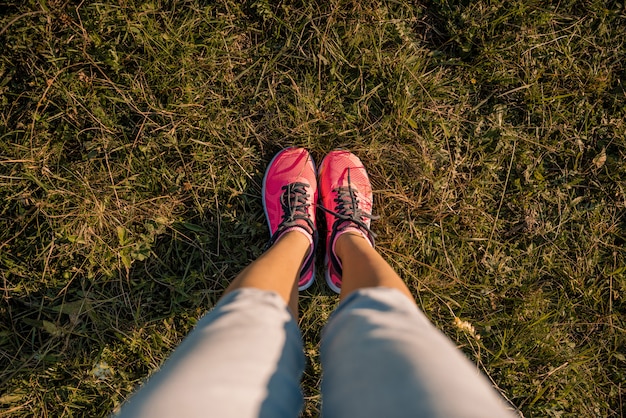 Young girl feet legs in sneakers on green meadow