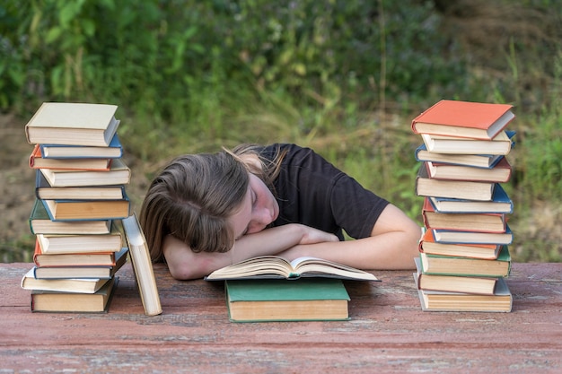 Young girl fell asleep after reading books on a wooden table in the garden