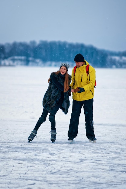 Young girl and fellow ice skating at the winter rink covered with snow in Trakai in Lithuania.