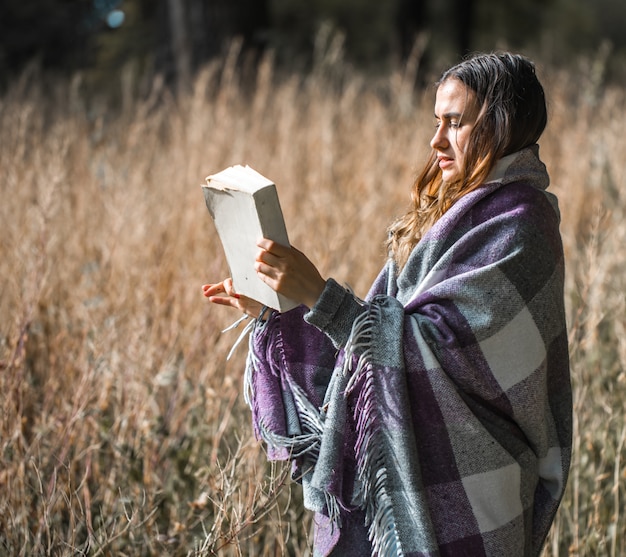 Photo young girl on a field reading a book