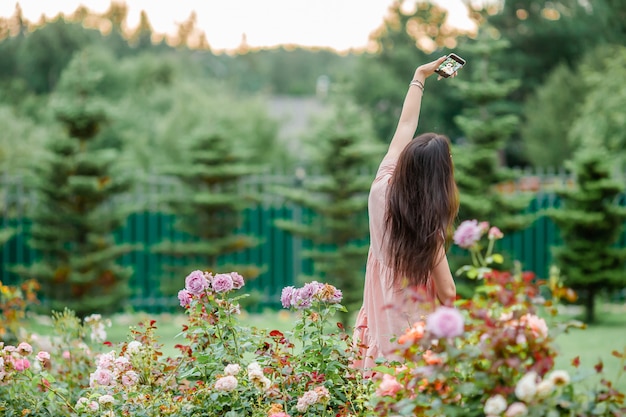 Young girl in a flower garden among beautiful roses. Smell of roses