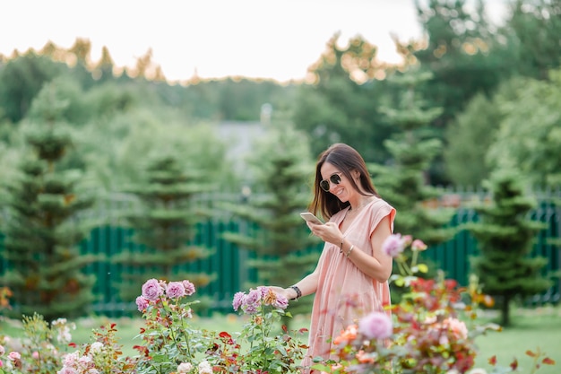 Молодая девушка в цветочном саду среди красивых роз. Запах роз