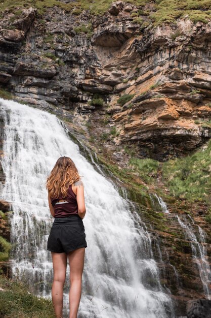 Foto ragazza davanti a un'enorme cascata chiamata cola de caballo nel parco nazionale di monte perdido