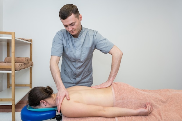 A young girl gets a back massage in a massage parlor beauty and\
health a male massage therapist and a client during a massage\
procedure