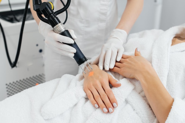 A young girl gets carbon peeling for the skin of her hands in a beauty salon Laser pulses cleanse the skin Hardware cosmetology The process of photothermolysis warming the skin