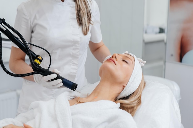 A young girl gets a carbon peeling for the skin of the neck in a beauty salon Laser pulses cleanse the skin Hardware cosmetology The process of photothermolysis warming the skin