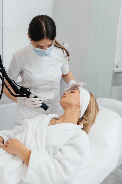 A young girl gets a carbon peeling for the skin of the neck in a beauty salon Laser pulses cleanse the skin Hardware cosmetology The process of photothermolysis warming the skin