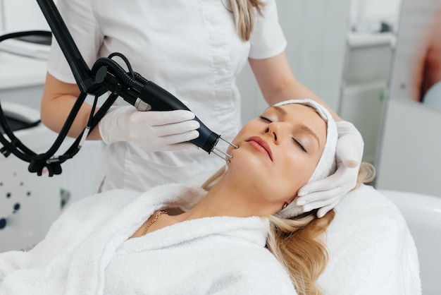 A young girl gets a charcoal peeling for the skin of the face in a beauty salon Laser pulses cleanse the skin Hardware cosmetology The process of photothermolysis warming the skin