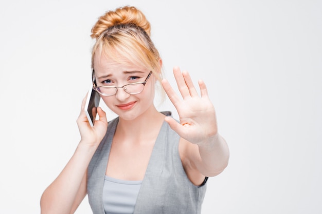 Young girl in glasses interrupted during important talking on mobile phone. Irritation, anger, annoyance of distraction