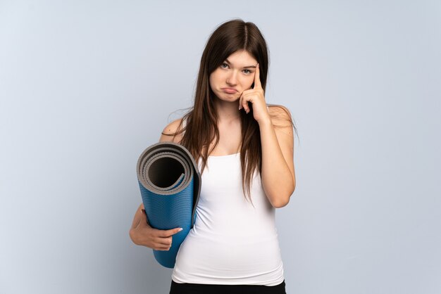 Young girl going to yoga classes while holding a mat thinking an idea