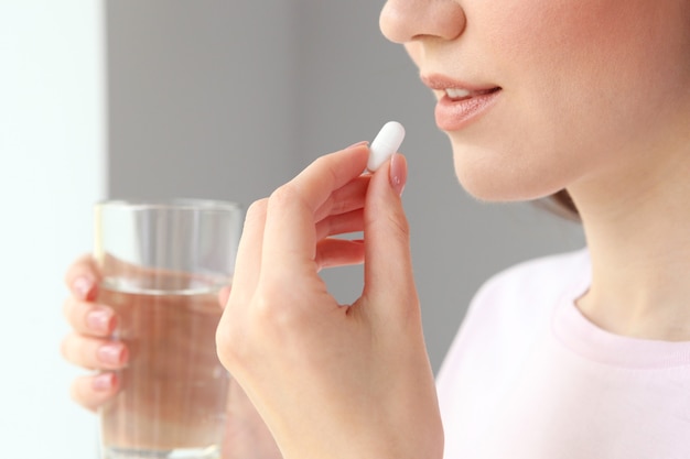 Young girl in a good mood takes pills at home