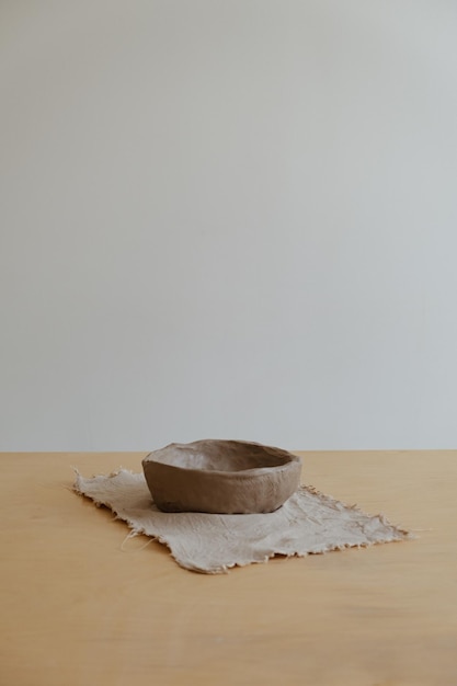 A young girl in a grey long sleeve makes a vase of clay with her own hands in a sculpture workshop