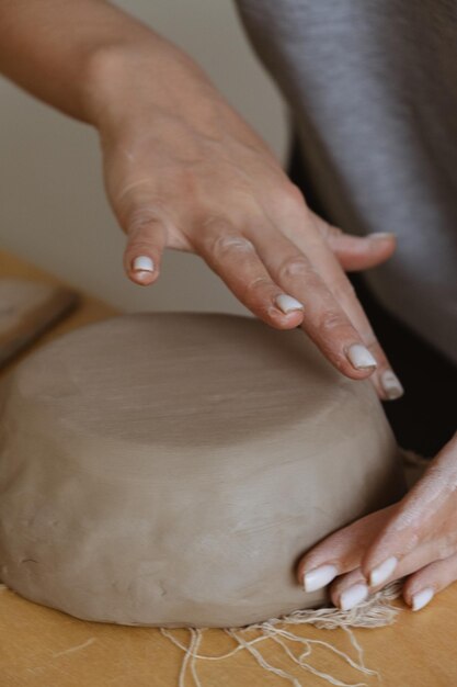 Photo a young girl in a grey long sleeve makes a vase of clay with her own hands in a sculpture workshop