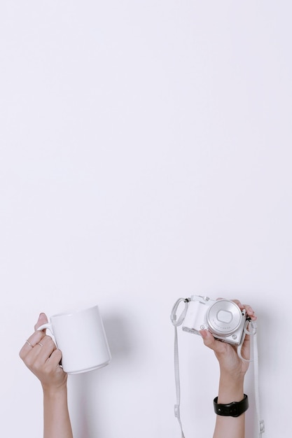 Young girl hands holding blank white mug or glass and camera Minimalist girly wallpaper