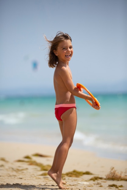 young girl happy with frisbee on the beach