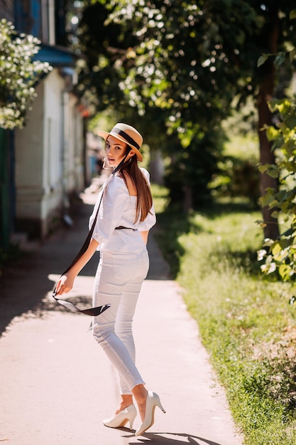 A young girl in a hat on the background of the blooming streets of the city