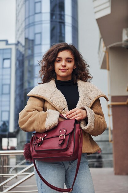 若い女の子は、ビジネスビルの近くの街で屋外散歩をしています