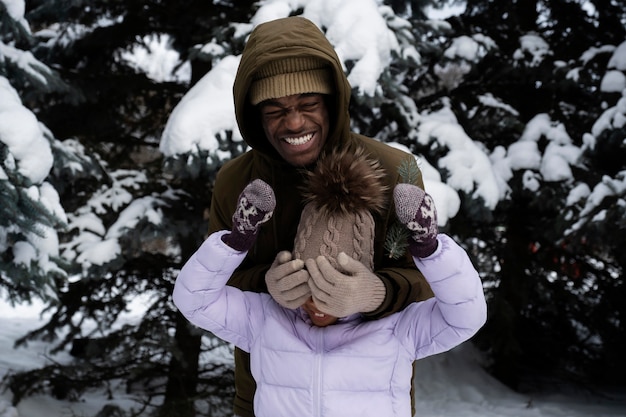 写真 雪の降る冬の日に父親と一緒に楽しんでいる少女