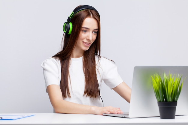 Young girl in headphones in the office listens to music