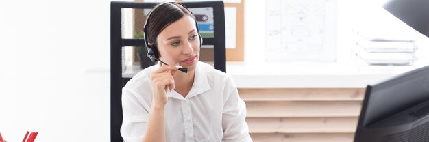 Photo a young girl in headphones with a microphone sitting at a computer table.