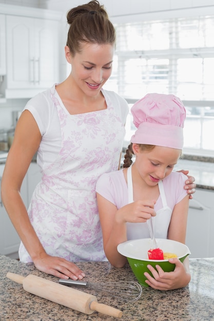 Young girl helping mother prepare food in kitchen