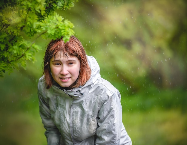 Фото Маленькая девочка прячется от дождя под кустом