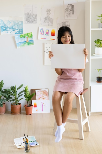 若い女の子は家でフレームと紙を保持します。家での趣味と芸術の研究