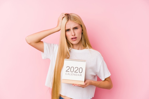 Молодая девушка, держащая шокированный календарь 2020 года, вспомнила важную встречу.