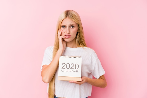 Young girl holding a 2020 calendar biting fingernails, nervous and very anxious.