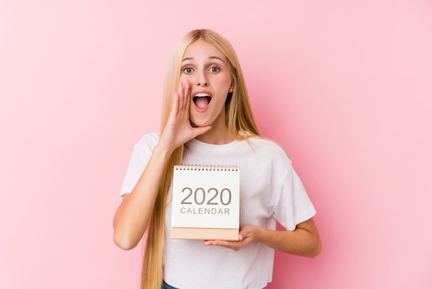 Young girl holding a 2020 calendar shouting excited to front.