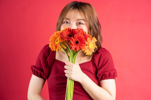 Young girl holding bouquet of gerberas with cheerful expression on pink