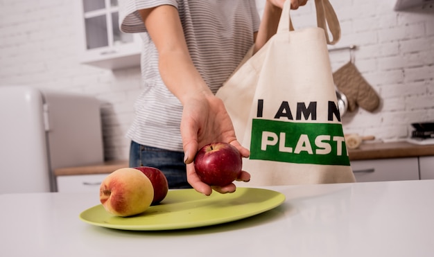 Foto ragazza che tiene una borsa di stoffa. in cucina. non sono di plastica.