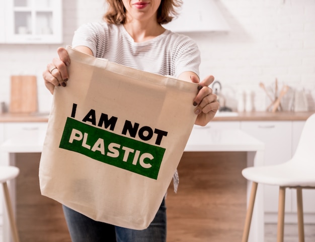 Ragazza che tiene una borsa di stoffa. in cucina. non sono di plastica.