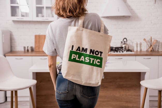 Ragazza che tiene una borsa di stoffa. in cucina. non sono di plastica.