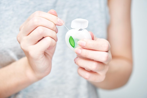 A young girl holding a dental floss on white background