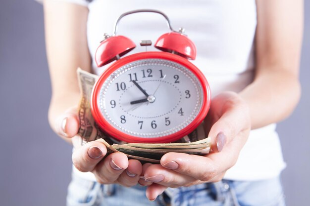 Young girl holding money and alarm clock