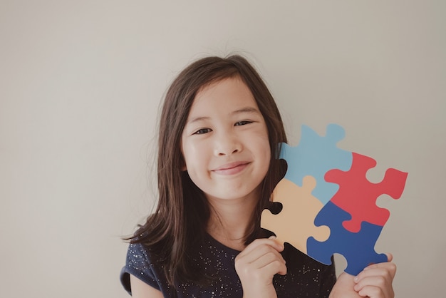 Foto ragazza giovane con puzzle jigsaw, salute mentale del bambino, giornata mondiale di sensibilizzazione sull'autismo