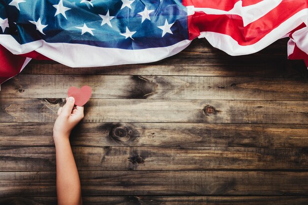 Young girl holding red heart cards in hands on American flag