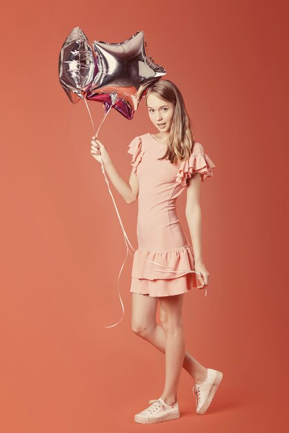 Young girl holding star balloons on red wall