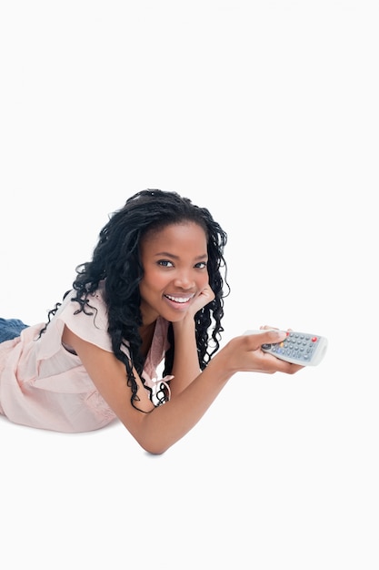 A young girl holding a television remote control is smiling at the camera