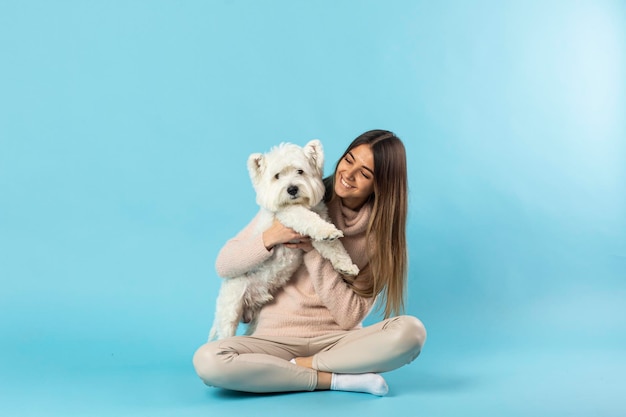 Young girl holding a white dog in her arms